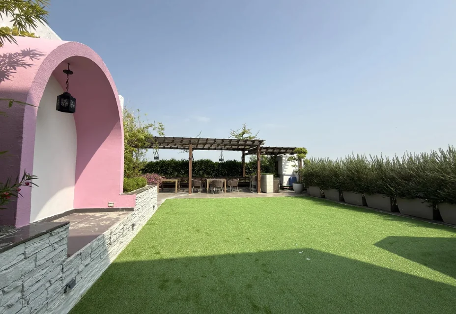 A terrace with a lawn and a pergola
