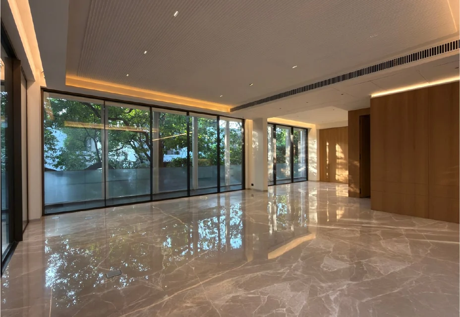 An empty drawing room with marble floors and tall windows