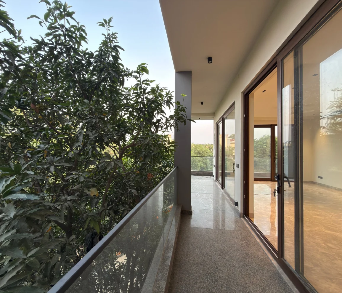 A balcony along a drawing room, with trees outside