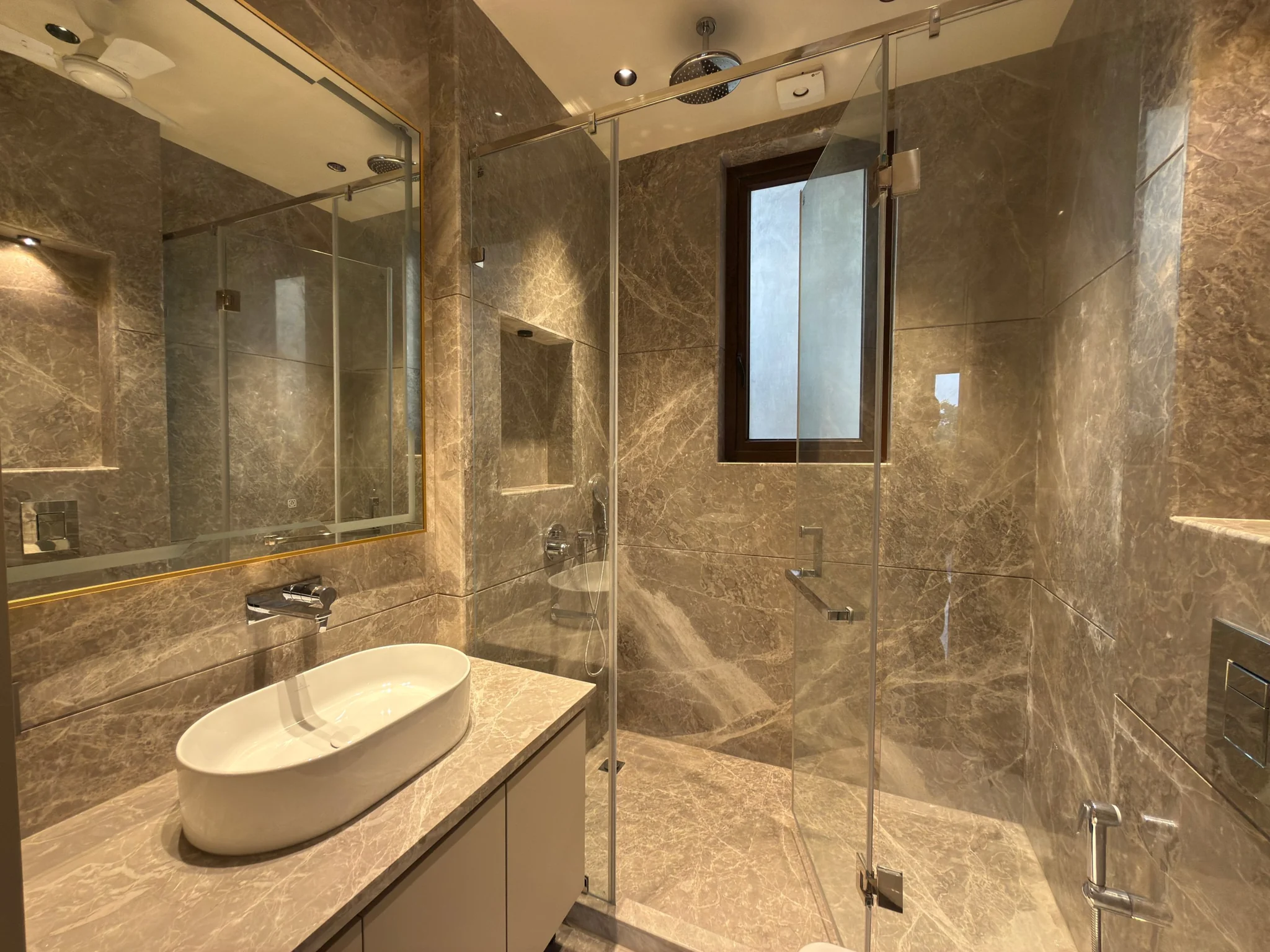 A bathroom in beige stone, with a glass shower
