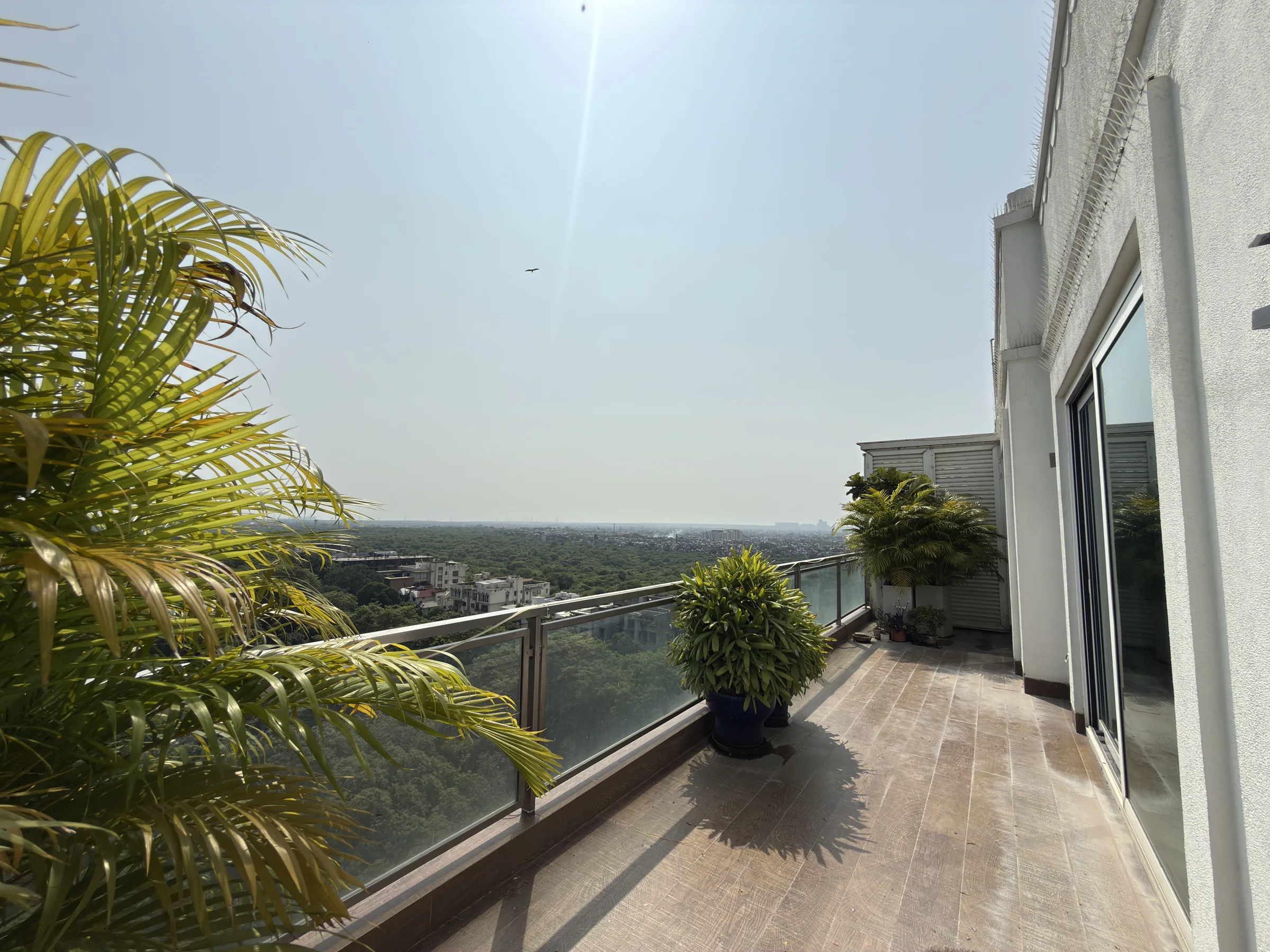 A long balcony with a wooden deck and a glass rail