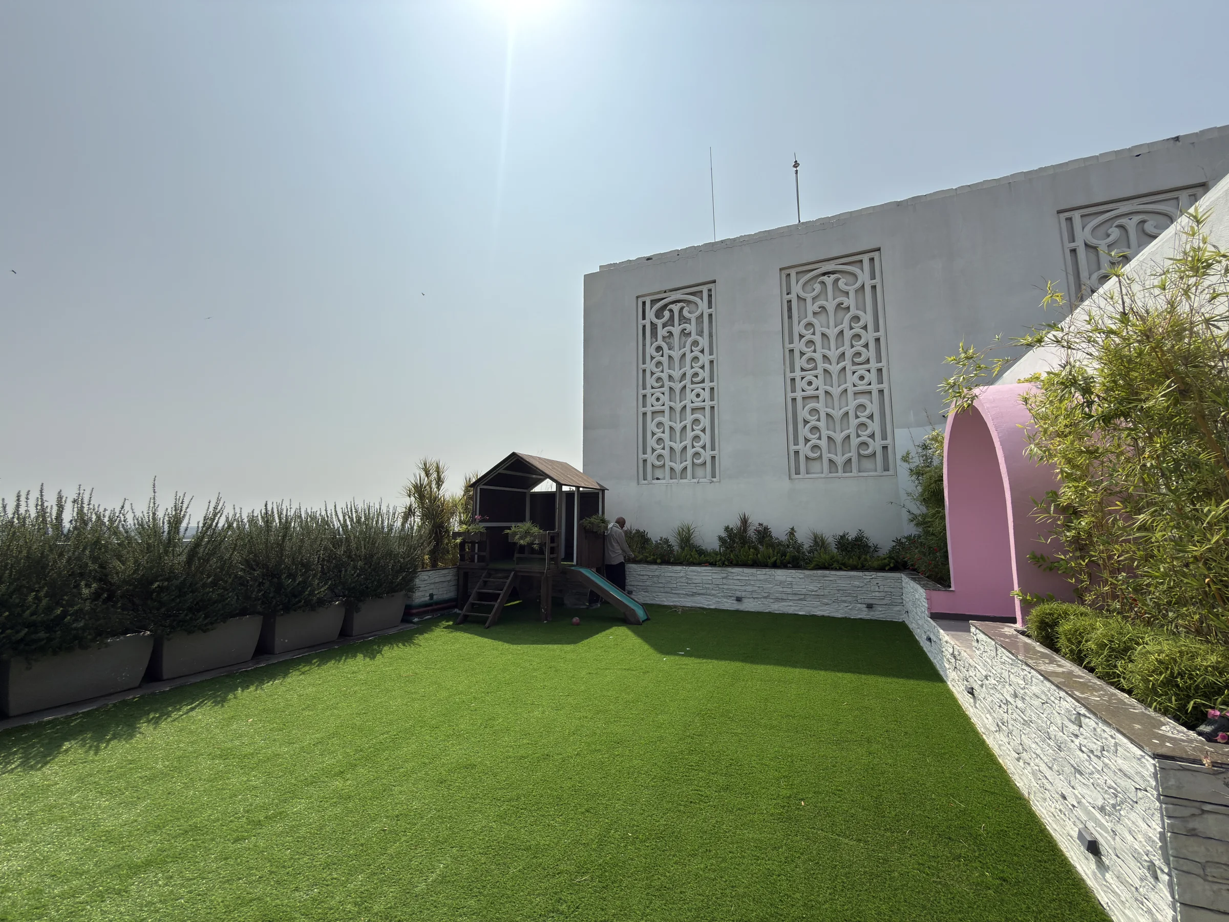 The terrace lawn, beside a white wall with carved screens