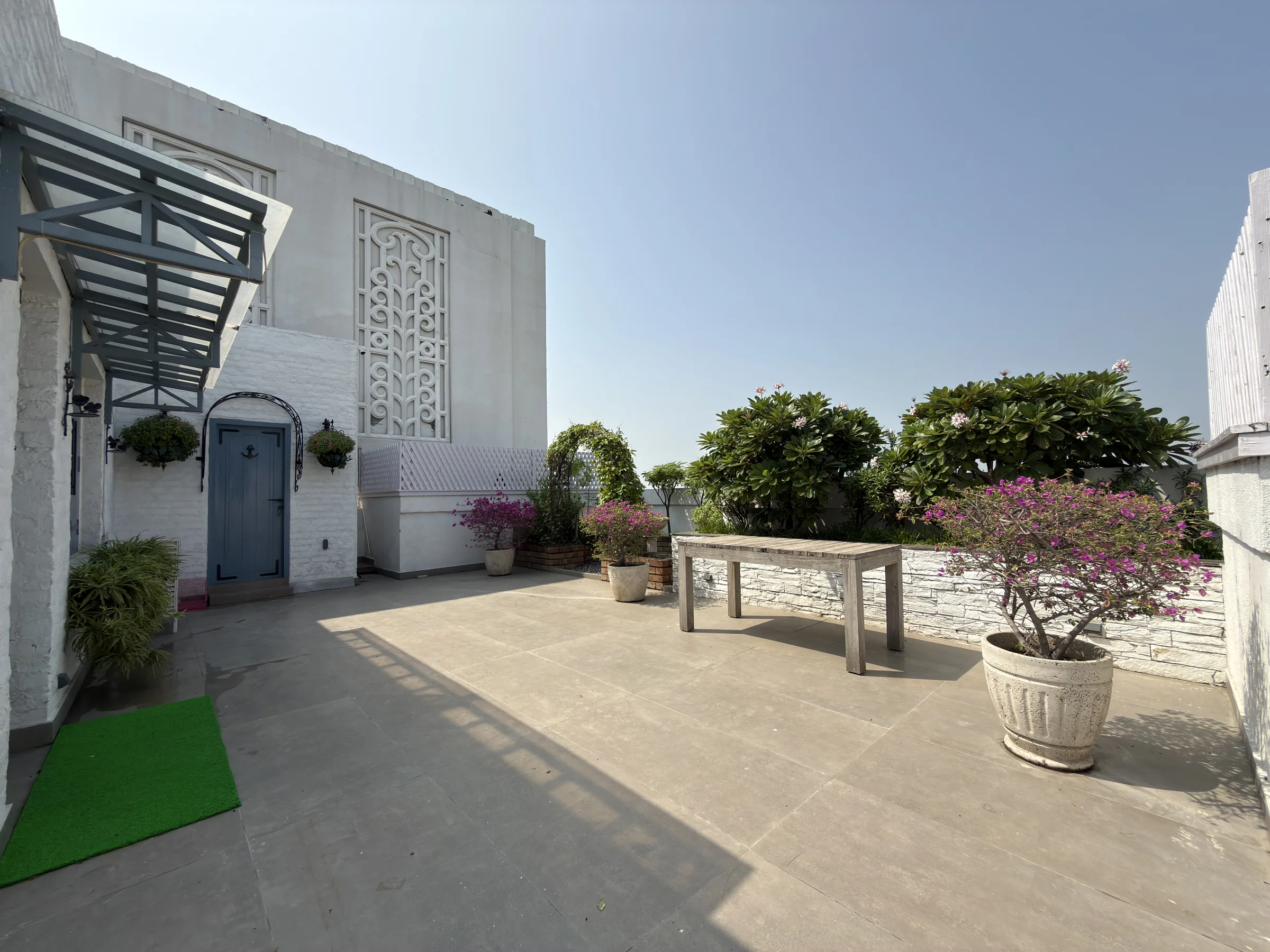 The paved part of the terrace, with a bench and flowering plants