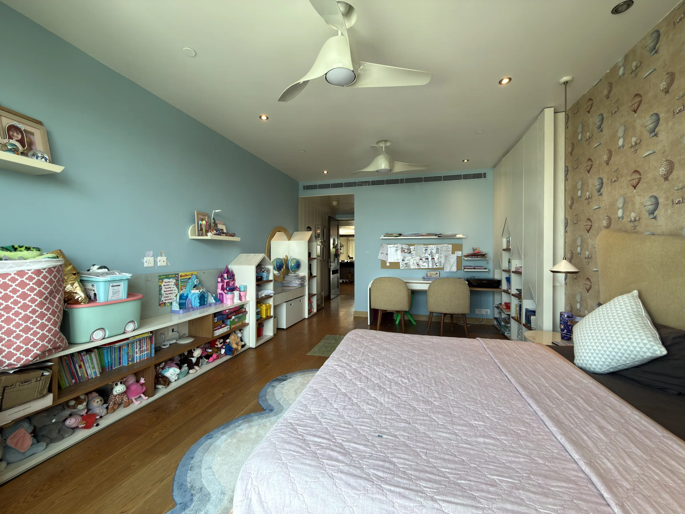A bedroom with long shelves and a study desk